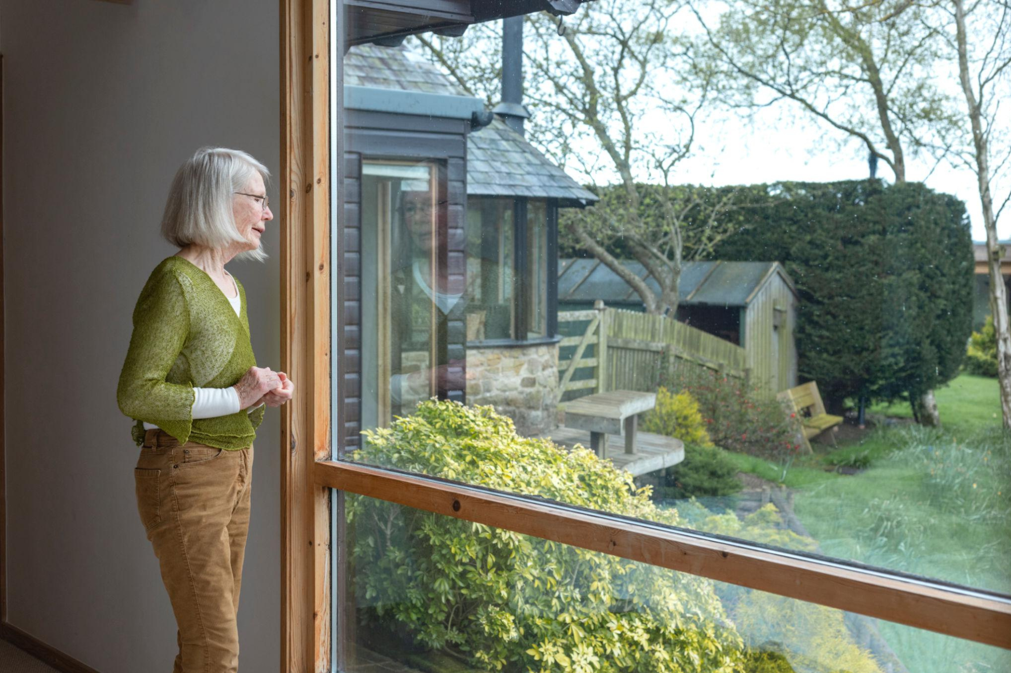 Lady staring out of window into garden.