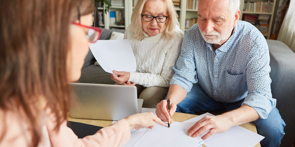 Two older people signing a document in regards to an LPA, with a younger solicitor.