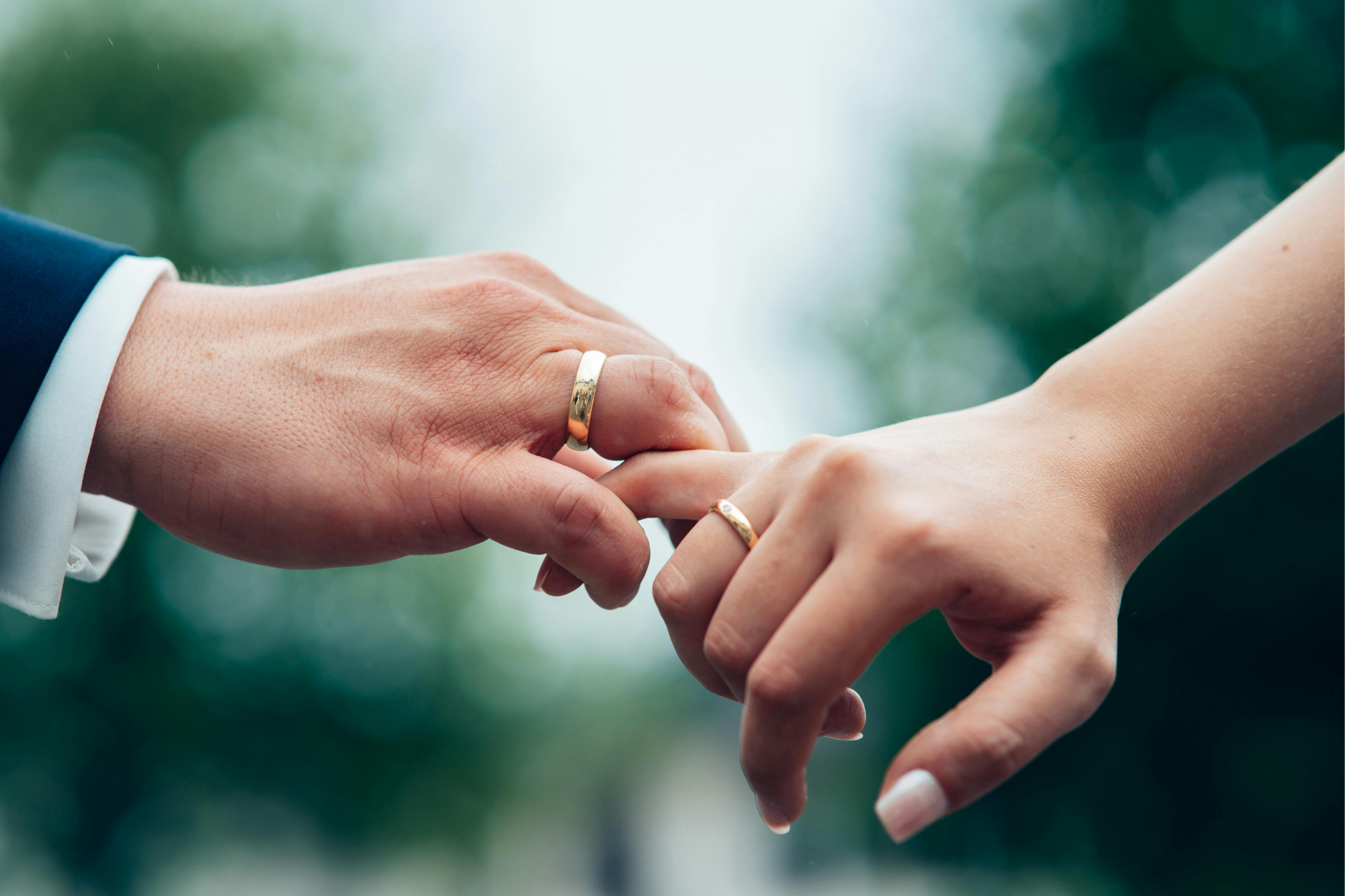 Two hands touching one another. Both has wedding rings on their ring fingers.