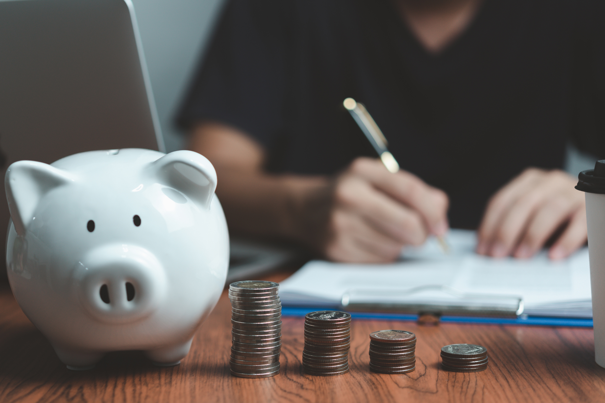 A person going through his finances. There's also a white piggy bank next to 4 small columns of money.